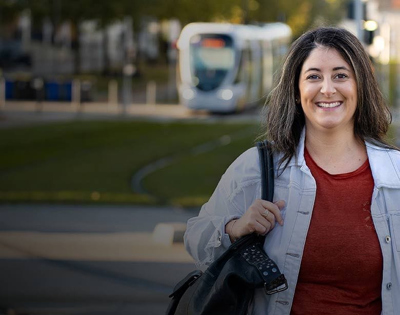 Nounou professionnelle souriant près d’un arrêt de tram