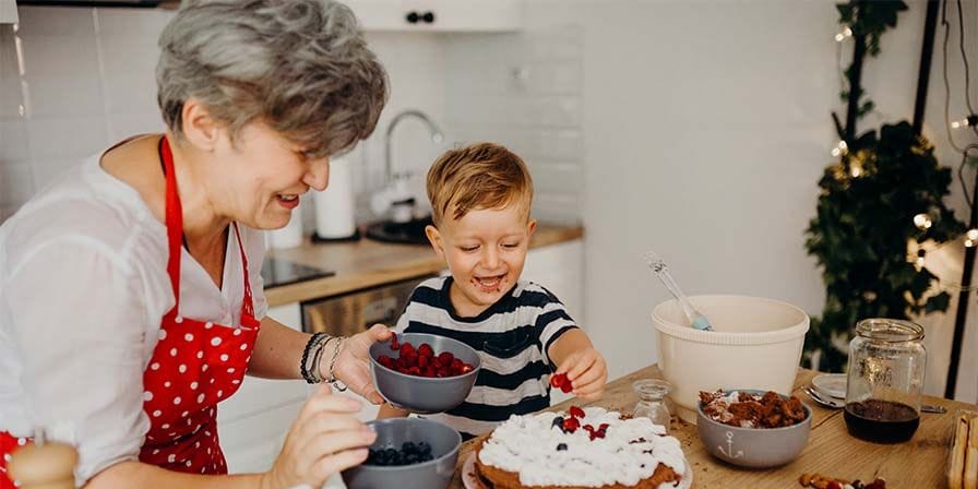 Nounou retraitée fait un gâteau avec un petit garçon