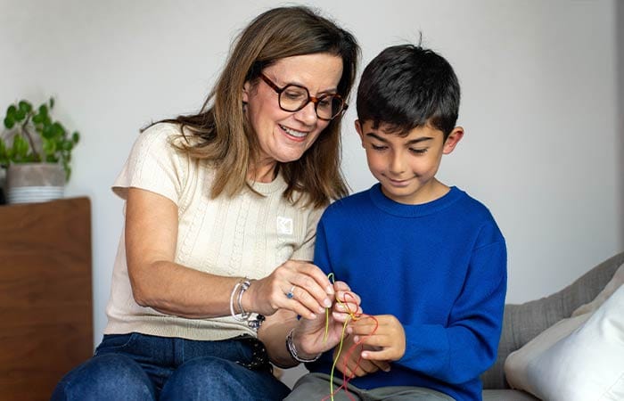 Nounou montrant à un garçon comment faire un bracelet tressé
