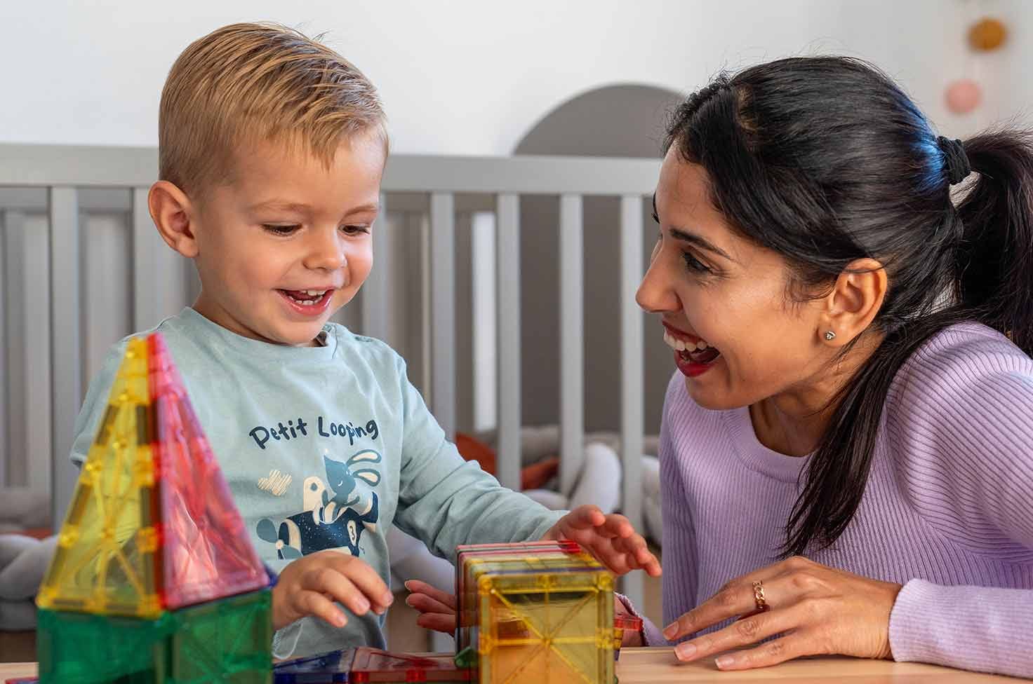Nounou et petit garçon riant autour d'une activité d'éveil