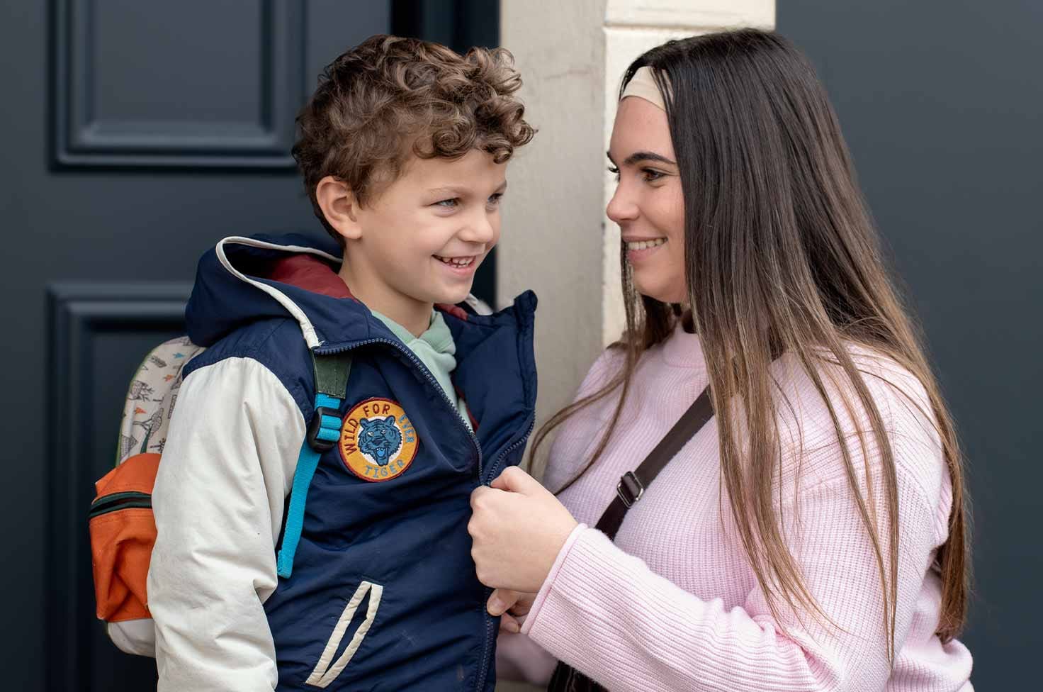 Nounou étudiante préparant un petit garçon pour l'emmener à l'école le matin
