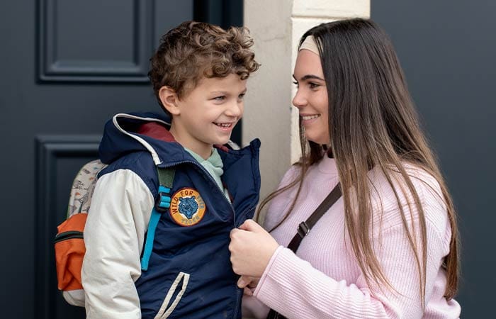 Nounou étudiante préparant un petit garçon pour l'emmener à l'école le matin