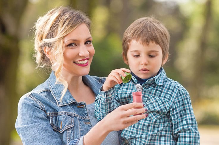 Nounou qui tient un tube pour qu'un petit garçon fasse des bulles