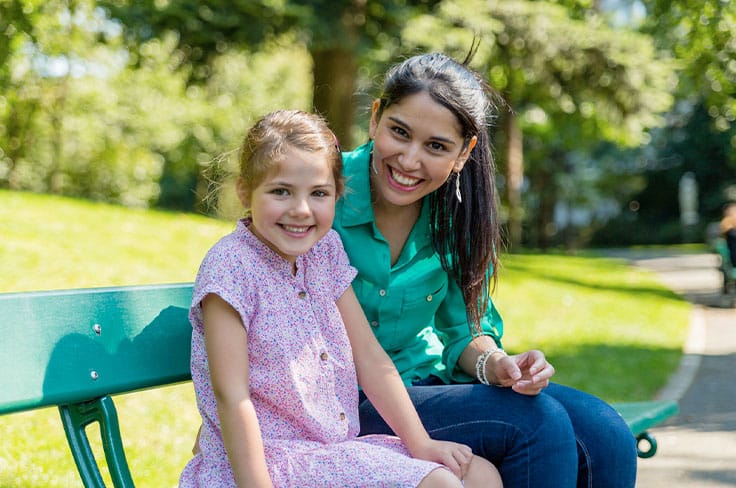 Nounou étudiante assise sur un banc avec une petite fille souriante