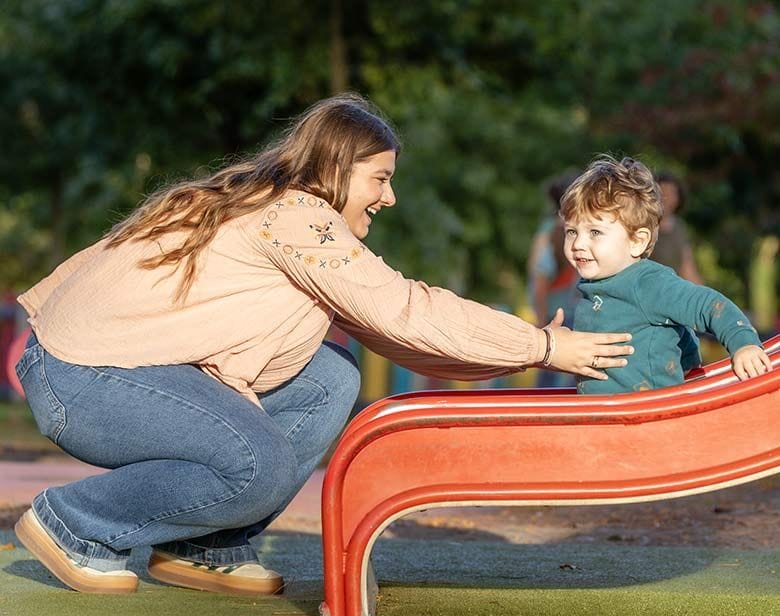 Petit garçon qui fait un toboggan avec sa nounou au parc